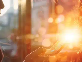 a person holding a smartphone with a glowing flare symbol appearing on the screen, surrounded by rays of light.