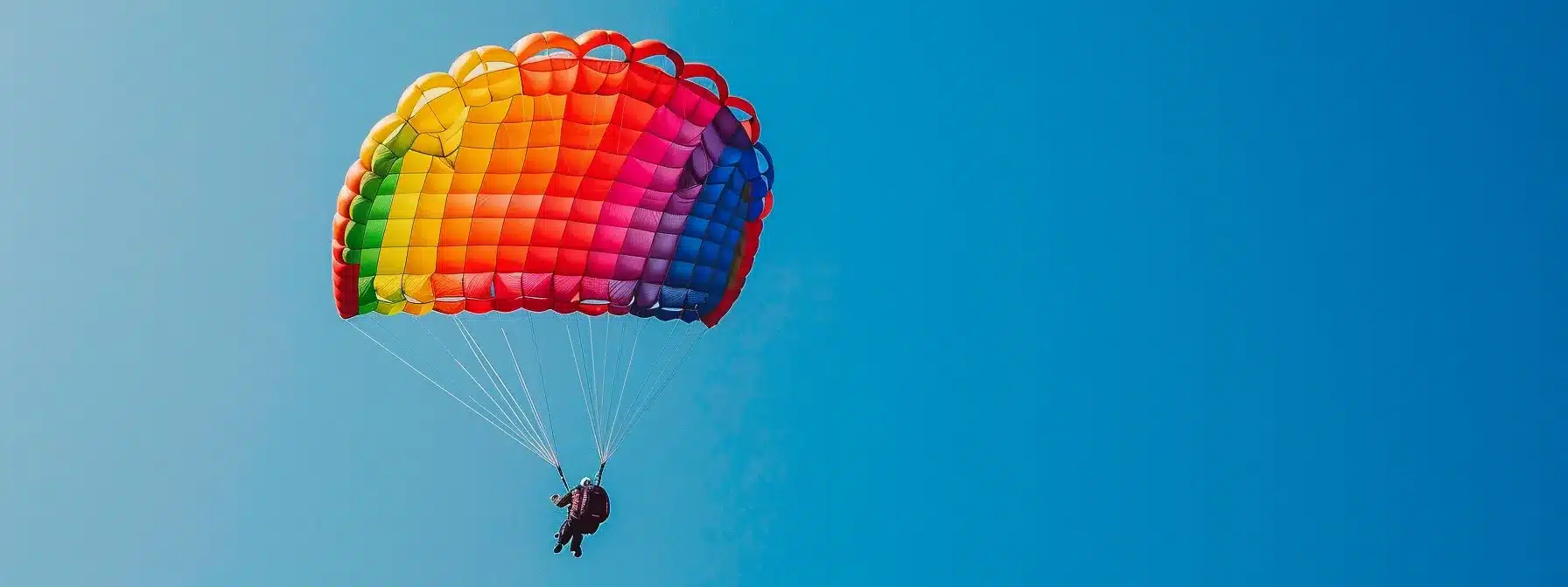 a vibrant rainbow-colored parachute soaring through a clear blue sky in the midst of a thrilling airdrop event.